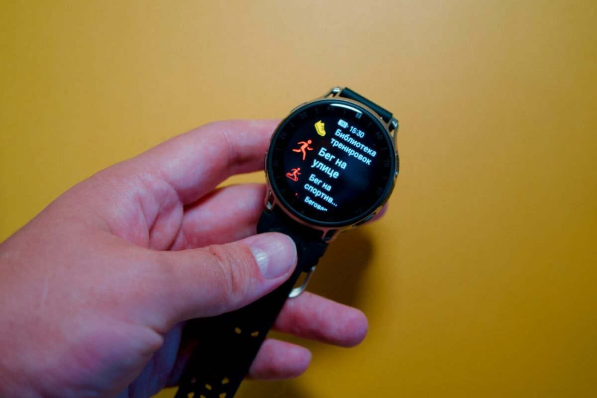 Hand holding a black smartwatch displaying fitness data.